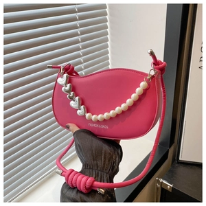 Detail of fuchsia crescent bag featuring pearl and silver heart chain accessories