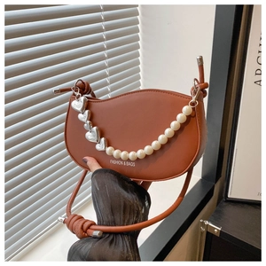 Detail of brown half-moon shoulder bag with pearl chain and silver heart pendant