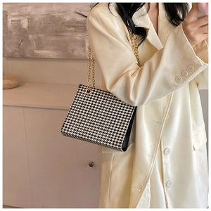 Detail of classic black and white houndstooth shoulder bag with gold metal chain straps