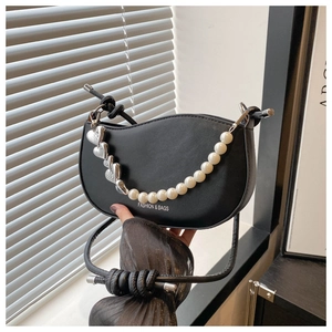 Detail of black crescent saddle bag with oversized pearl chain and silver heart charms