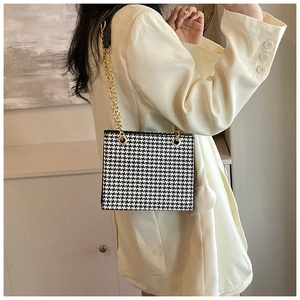 Chic houndstooth woven tote bag with gold chain strap worn by a model in beige blazer