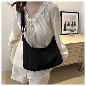 Detail of black nylon hobo bag featuring wide fabric strap and silver adjustable buckle