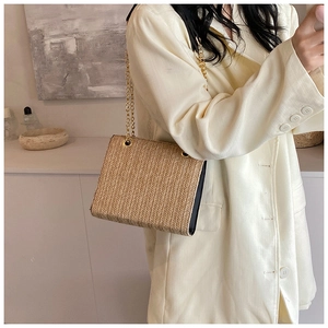 Detail of woven straw shoulder bag featuring textured finish and gold metal chain strap