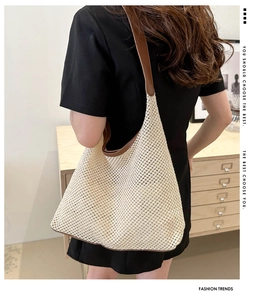 Détail d'un grand sac cabas en maille tissée beige avec des anses en cuir marron foncé