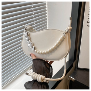 Detail of white saddle bag with heart pearl chain and knot shoulder strap