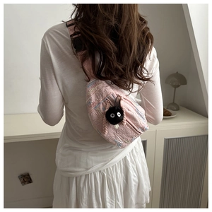 Detail of pink quilted crossbody bag with colorful stitching and fuzzy charm