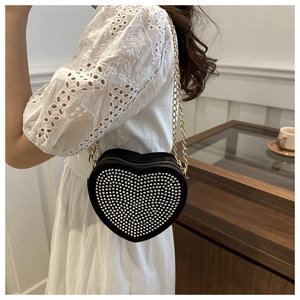 Detail of a heart-shaped crossbody bag with silver studs and gold metal chain