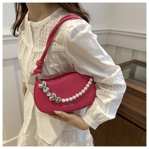 Detail of rose pink crescent bag featuring silver heart chain and pearl accents