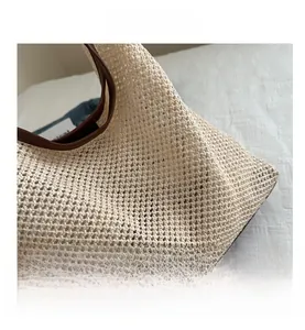 Détail du sac cabas en paille tissée beige avec anse en cuir marron et maille ajourée