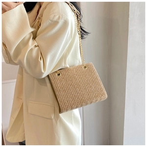 Detail of woven straw shoulder bag featuring V-shaped texture and golden chain strap