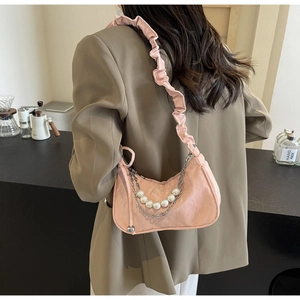Detail of pink pleated underarm bag with pearl strap and silver chain on model