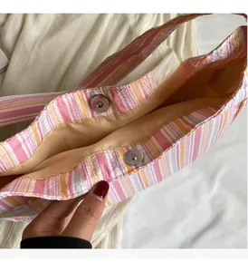 Detail view of metallic magnetic closure on a colorful striped casual nylon tote bag