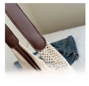 Gros plan du sac en paille tissé avec bandoulière en cuir marron et surpiqûres