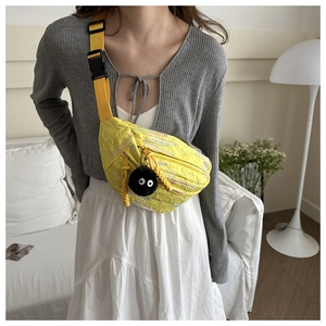 Detail of yellow crossbody chest bag with colorful embroidery and cute plush pendant