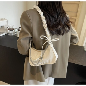 Détail d'un sac à bandoulière blanc crème avec chaîne en perles et sangle à volants