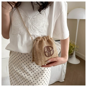 Gros plan détaillé d'un sac seau en paille tressée avec logo BB en cuir circulaire