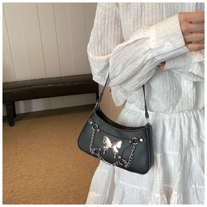 Detalle de bolso media luna negro con hebilla de mariposa plateada y cadenas modernas