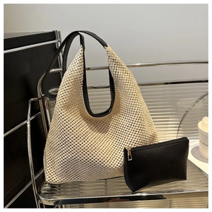 Detail of beige woven straw tote bag with black shoulder straps and inner pouch