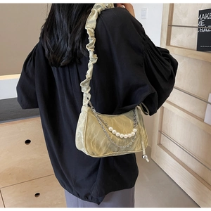 Détail du sac croissant vert clair avec chaîne de perles et texture de bandoulière plissée
