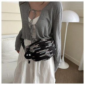 Detail of black crossbody bag with colorful wave embroidery and plush eye charm on a model