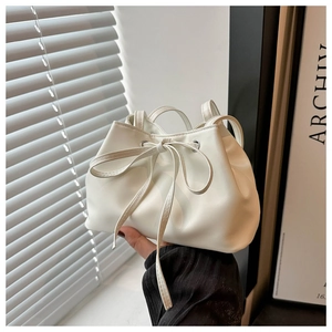 Detail of white leather bucket bag with bow drawstring on minimalist background