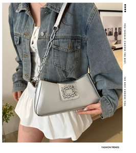 Detail of silver chain shoulder bag with oversized rhinestone buckle on denim outfit