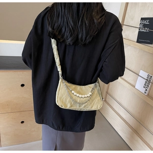 Detailed view of ruched green underarm bag featuring pearl chain and model styling