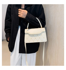 Detail of beige quilted handbag with gold heart studs and stylish wavy flap design