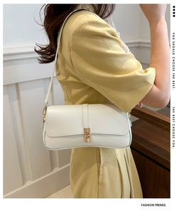 Gros plan sur le sac sous le bras en cuir blanc avec fermoir doré sur robe jaune