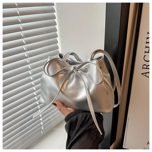 Detail of silver metallic bucket bag with drawstring bow and reflective pearl finish