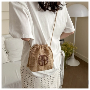 Détail de la texture du sac seau en paille tissée avec écusson AB en cuir
