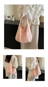 Detailed side view of a pleated striped nylon tote bag with pink and orange vertical stripes