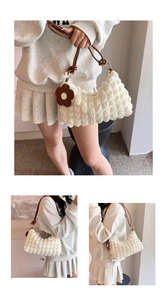 Detail of white bubble texture tote bag with brown leather strap and flower charm