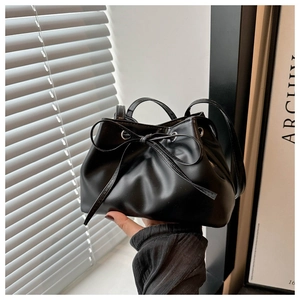 Detail of black leather bucket bag with adjustable ribbon drawstring and soft texture
