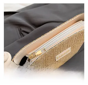 Dettaglio borsa in paglia intrecciata con cerniera dorata e rifiniture in pelle
