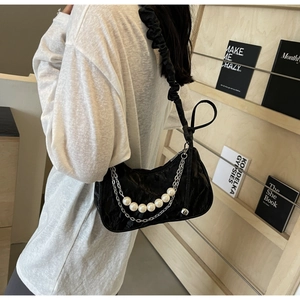 Detailed side view of a black crescent shoulder bag with white pearls and chain