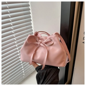 Detailed view of pink bucket bag featuring a decorative bow and silver metal eyelets
