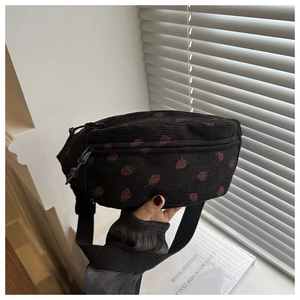 Detailed close-up of a black corduroy chest bag featuring a cute red strawberry print
