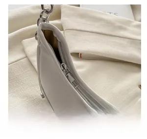Detailed macro view of smooth silver metal zipper on cream white PU leather shoulder bag