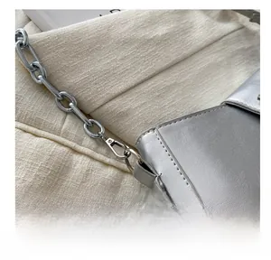 Macro shot of silver PU leather bag with metallic chain and lobster clasp connection