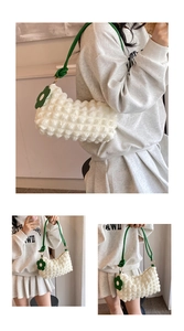 Detail of white textured bubble cloud bag with green cord strap and flower charm