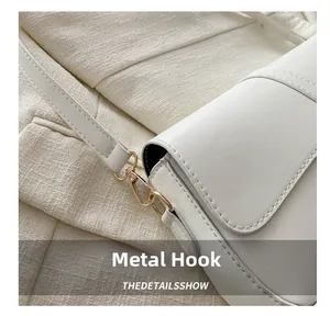 Détail du crochet en métal doré clair et des coutures fines sur un sac bandoulière crème