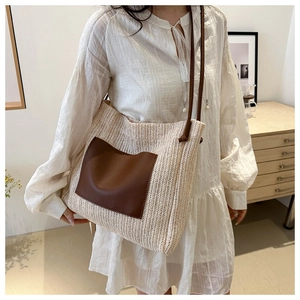 Detail of beige straw woven tote bag featuring brown leather pocket and thin shoulder strap