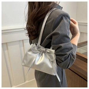 Detail of silver metallic shoulder bag with bow knot and stylish pleated texture
