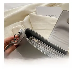 Detail view of silver shoulder bag showing smooth zipper and metallic magnetic buckle