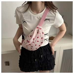 Pink corduroy crossbody bag with strawberry print shown on model in cozy home setting