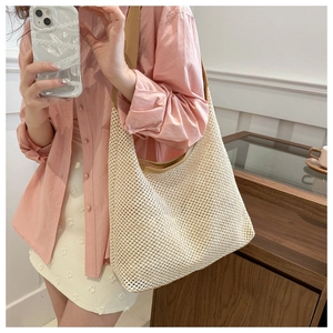 Close-up of beige woven beach tote featuring mesh texture and brown faux leather straps