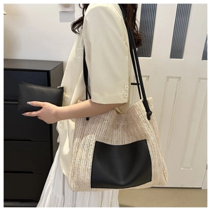 Detail of woven straw tote bag featuring a black leather patch pocket and shoulder straps