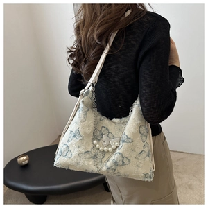 Close-up of canvas tote bag with blue butterfly print, silver chain and pearl charms