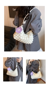 Detail view of stylish cream shoulder bag with bubble texture and floral pendant